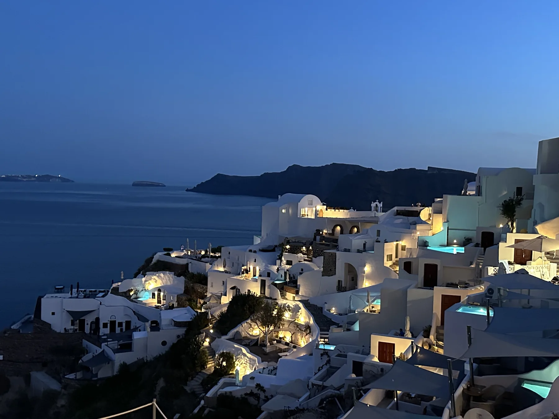 White hillside buildings illuminated at dusk in Santorini